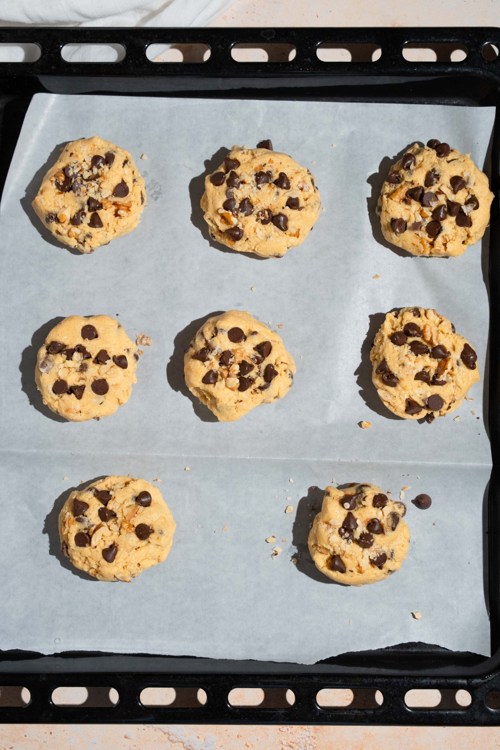 A lined baking sheet with several uncooked Neiman Marcus chocolate chip cookies.