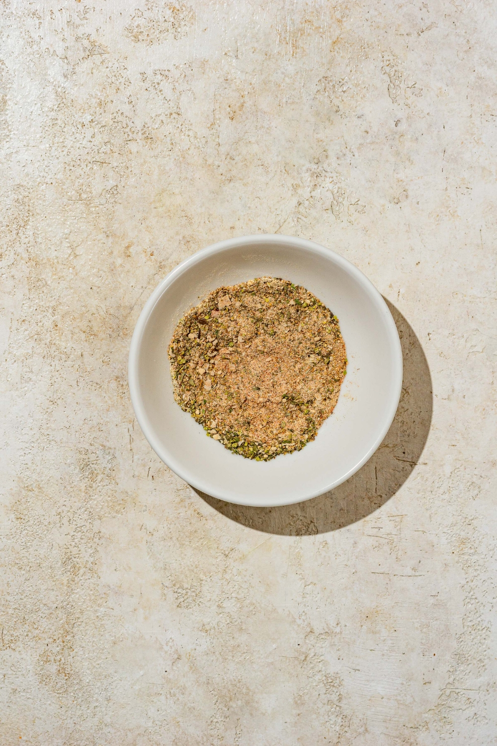A small bowl of mixed seasonings. The bowl is on a tan counter.