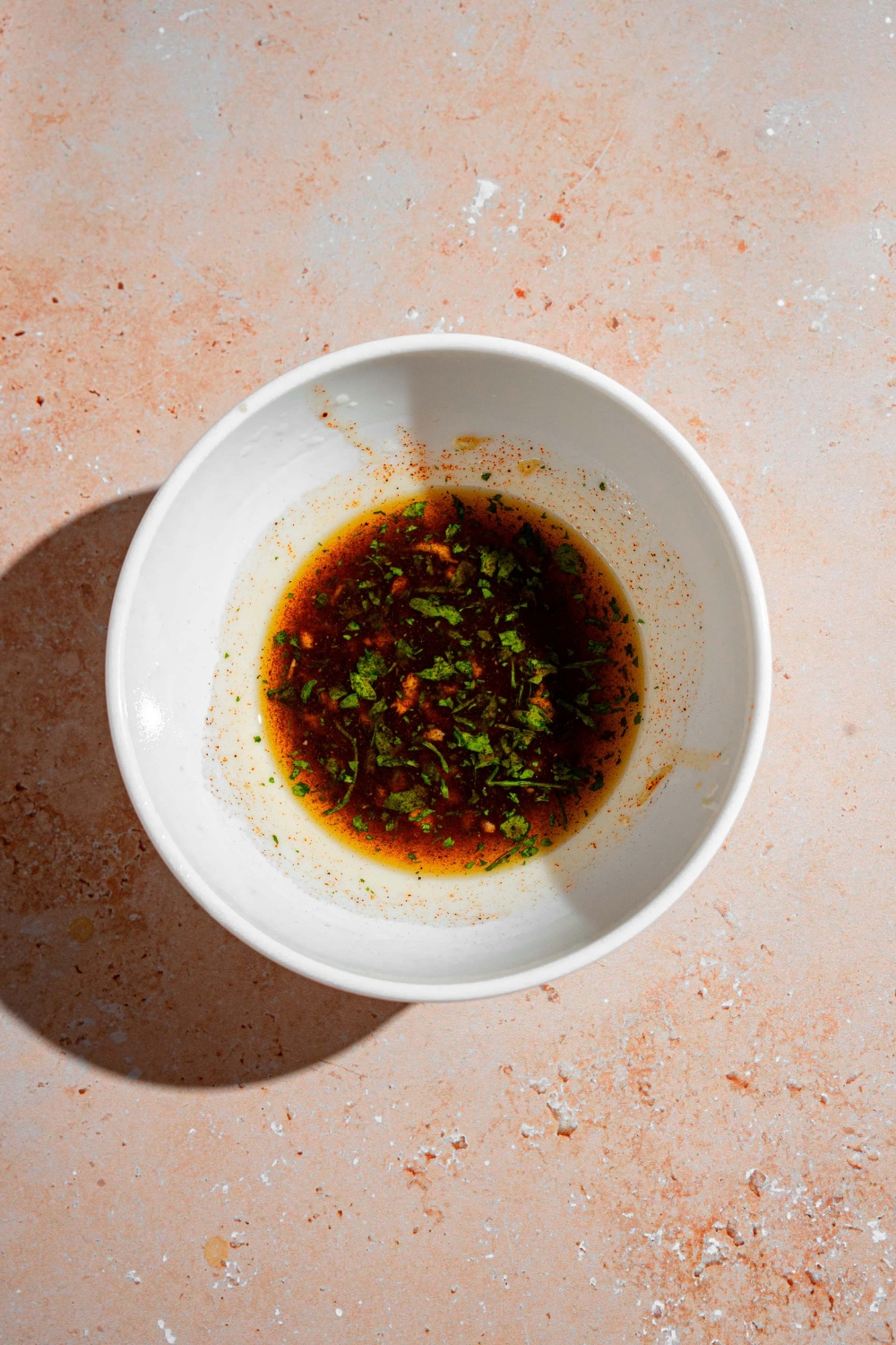 A small bowl with a garlic lemon oil mixture. The bowl is on a tan counter.