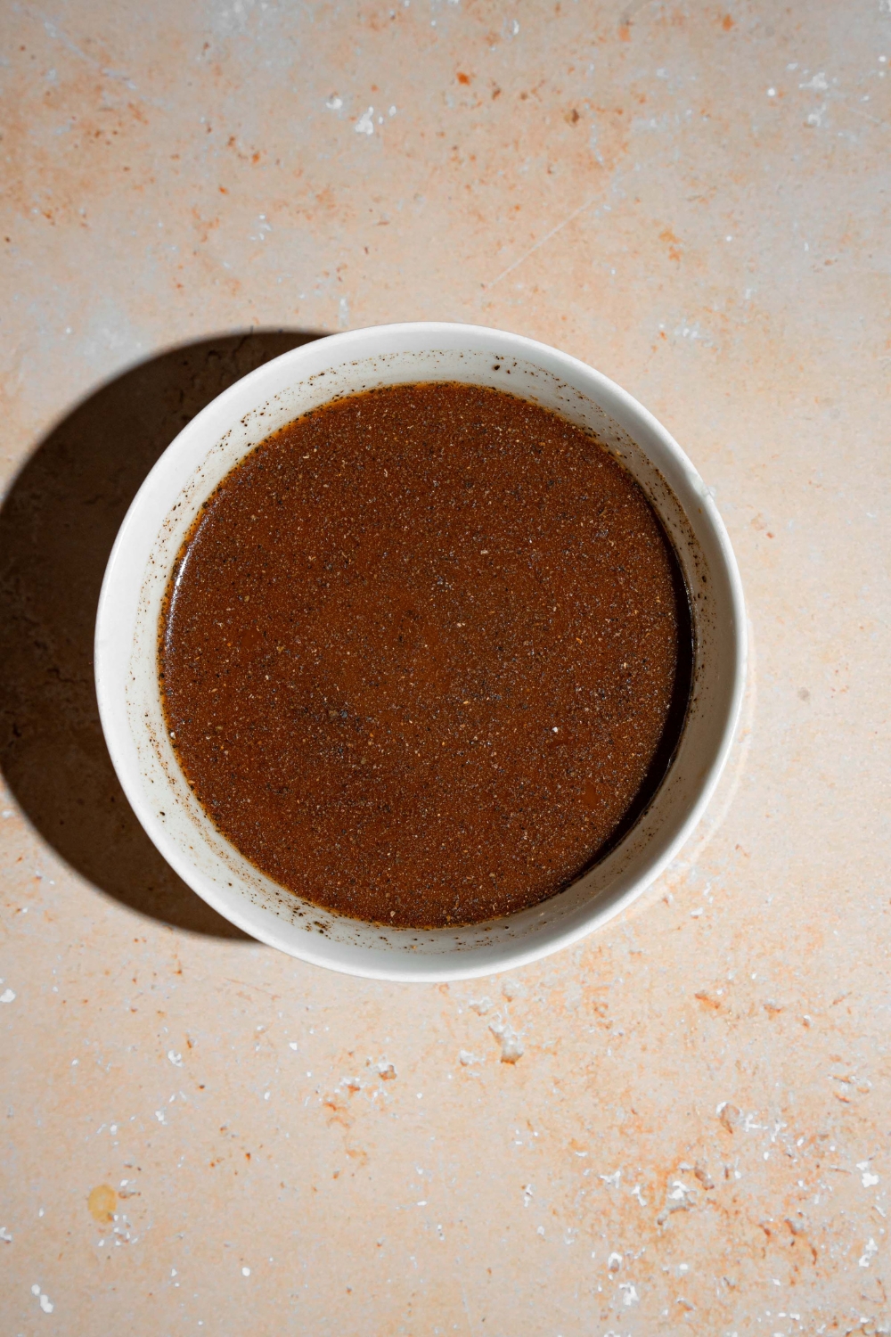 A white bowl with pepper steak sauce. The bowl is on a tan counter.