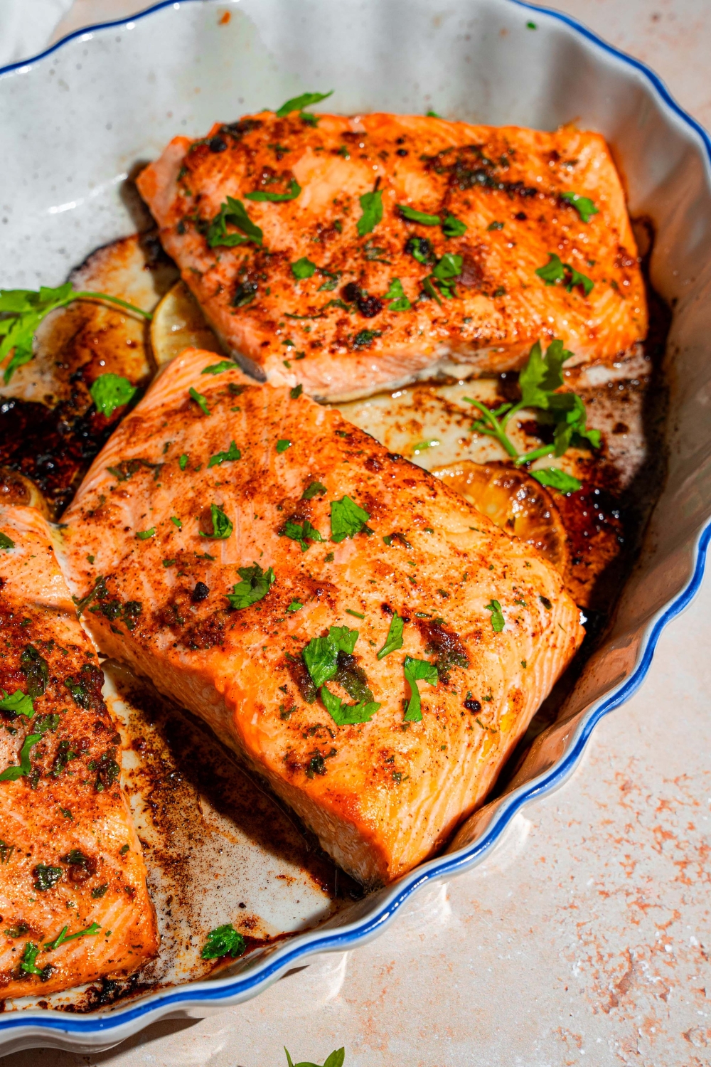 A baking dish with several pieces of baked Sockeye salmon garnished with fresh parsley.