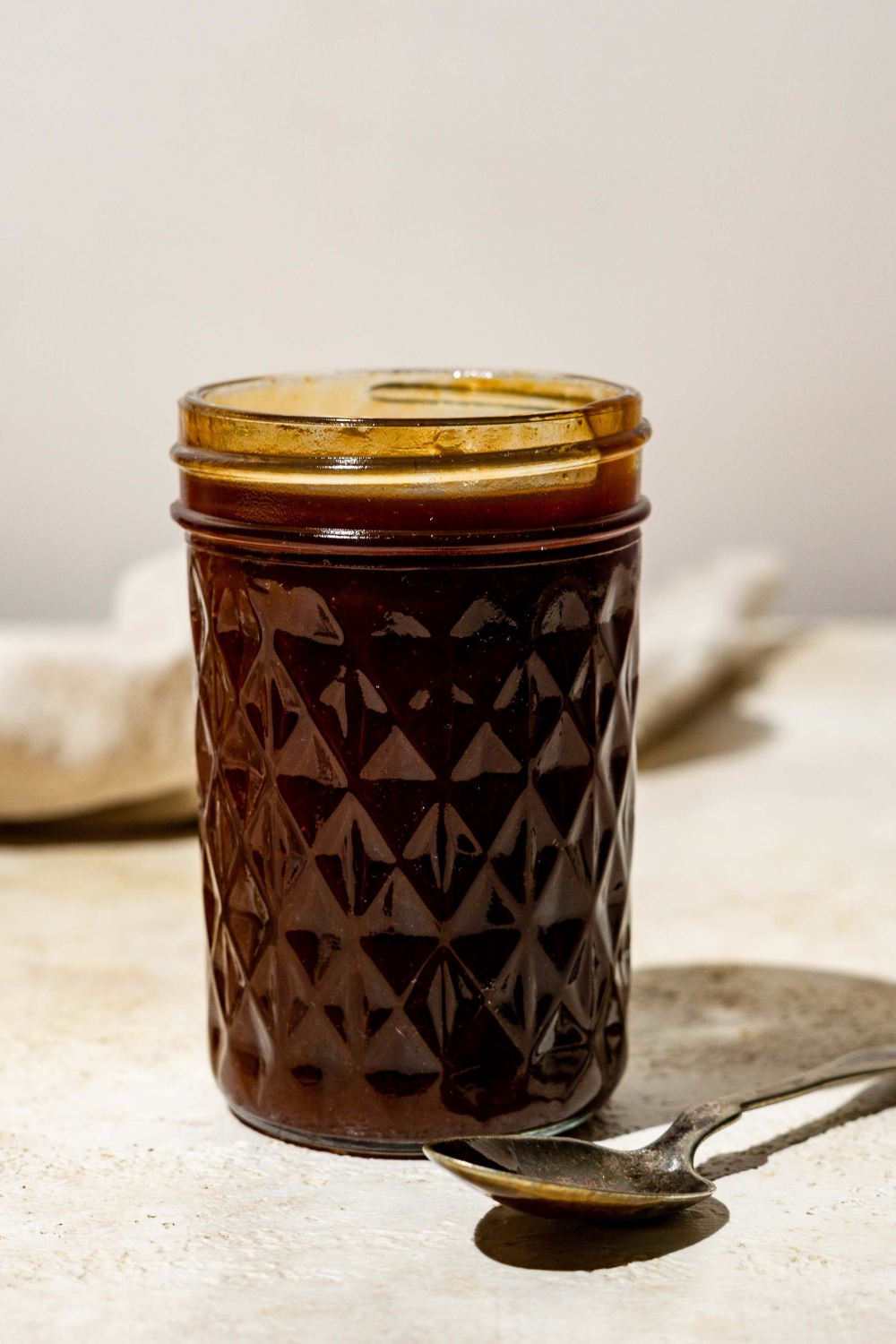 A mason jar filled with chicken Katsu sauce. The jar is on a tan counter with a spoon.
