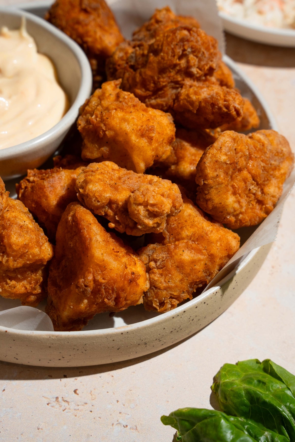 Homemade Chick Fil A nuggets and sauce on a white plate lined with parchment paper.