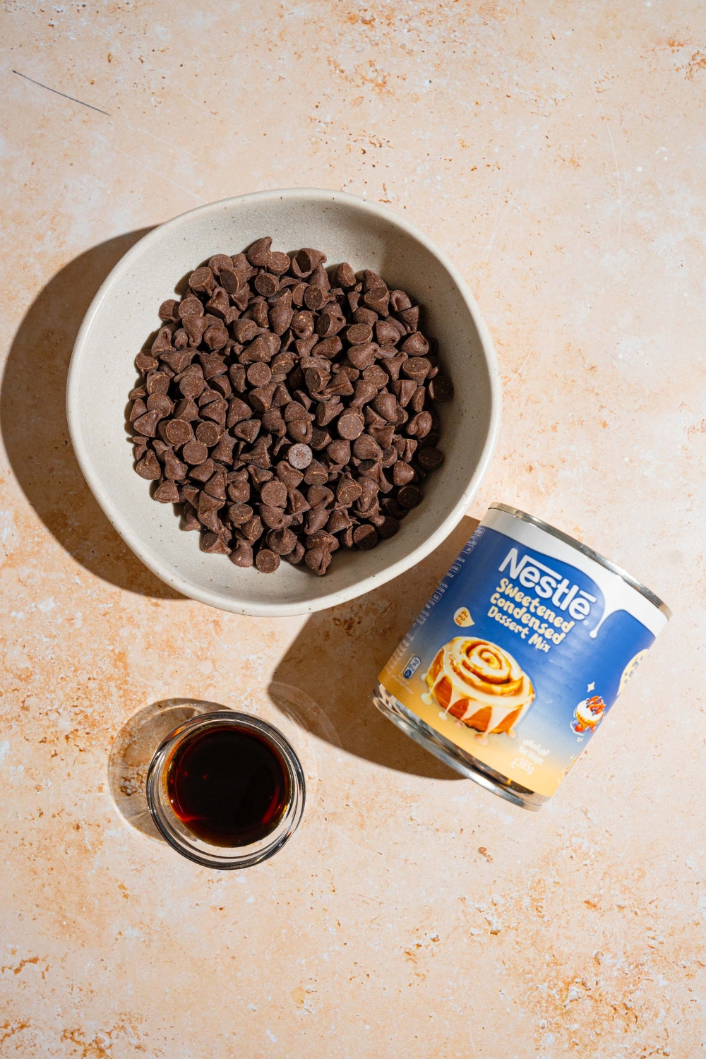 An overhead shot of ingredients to make fudge with condensed milk including chocolate chips, a can of condensed milk, and vanilla.