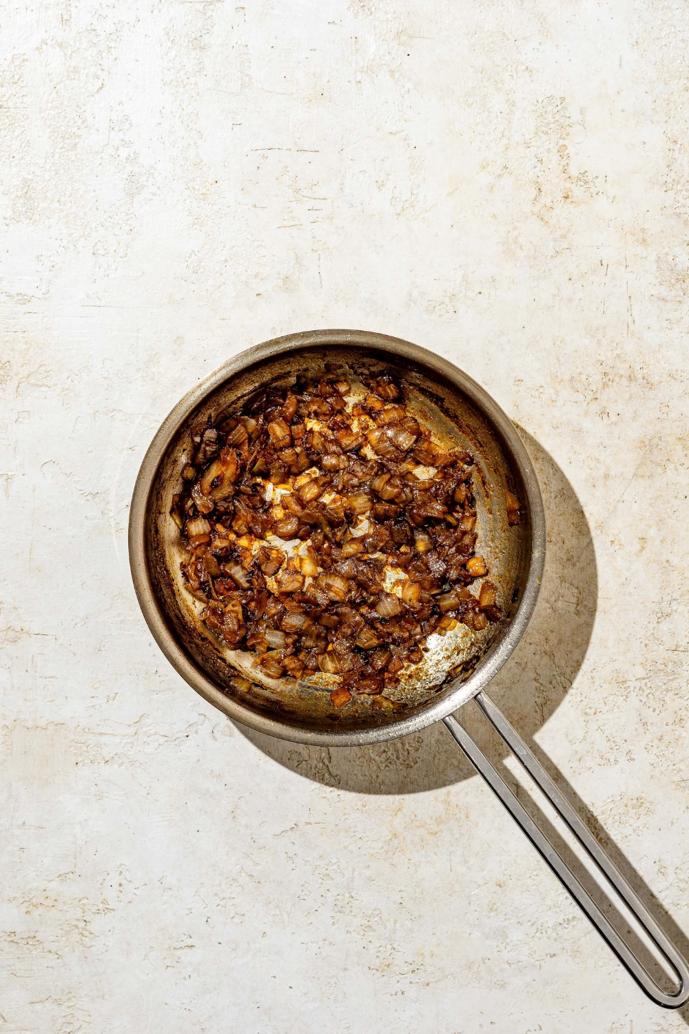 A skillet with caramelized onions. The skillet is on a tan counter.