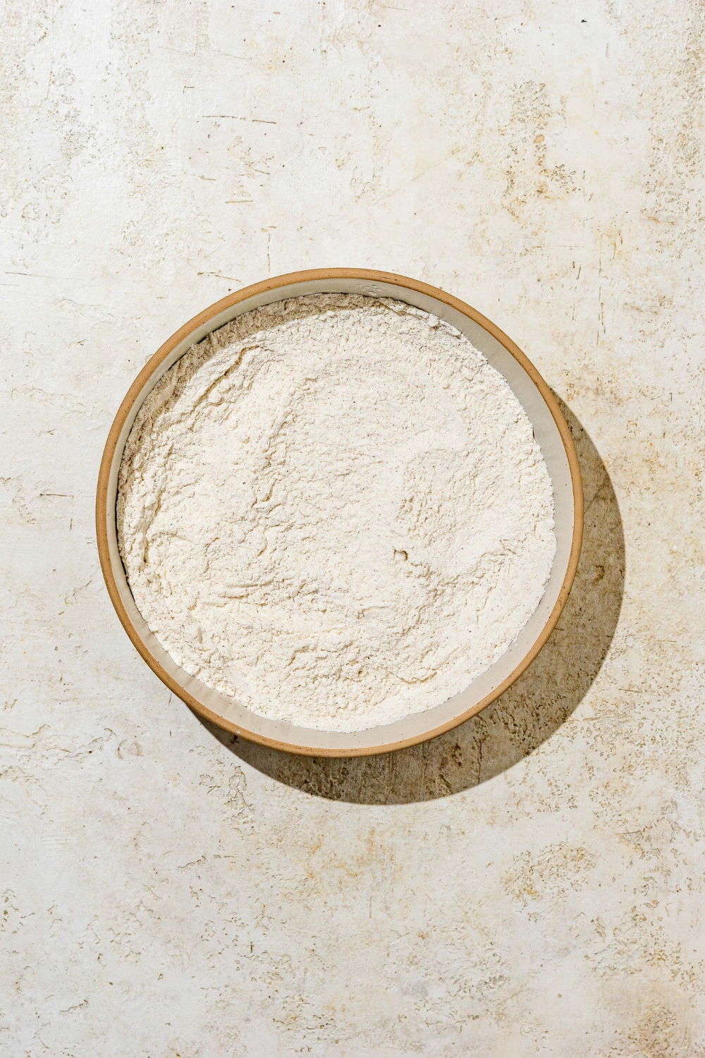 A large bowl with a breading mixture. The bowl is on a white counter.