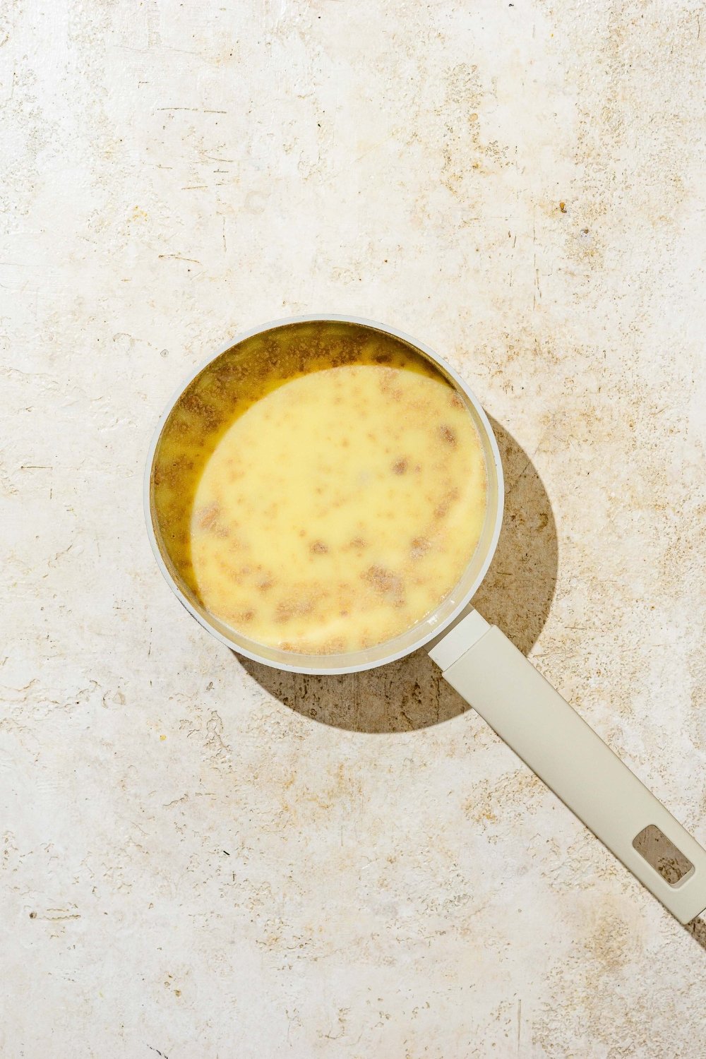 A saucepan with melted butter and cinnamon mixture. The saucepan is on a tan counter.