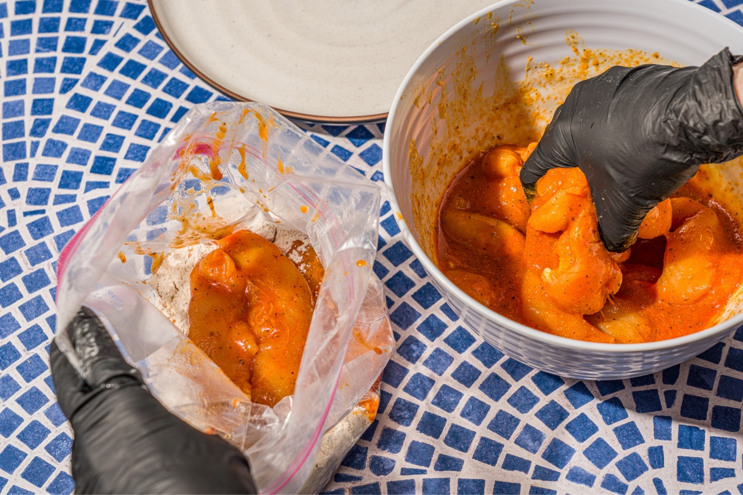 A hand placing marinated chicken tenders from a bowl into a bag of seasoned chicken coating.