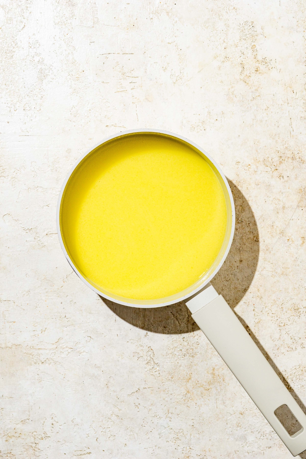 A saucepan with melted butter. The pan is on a white counter.