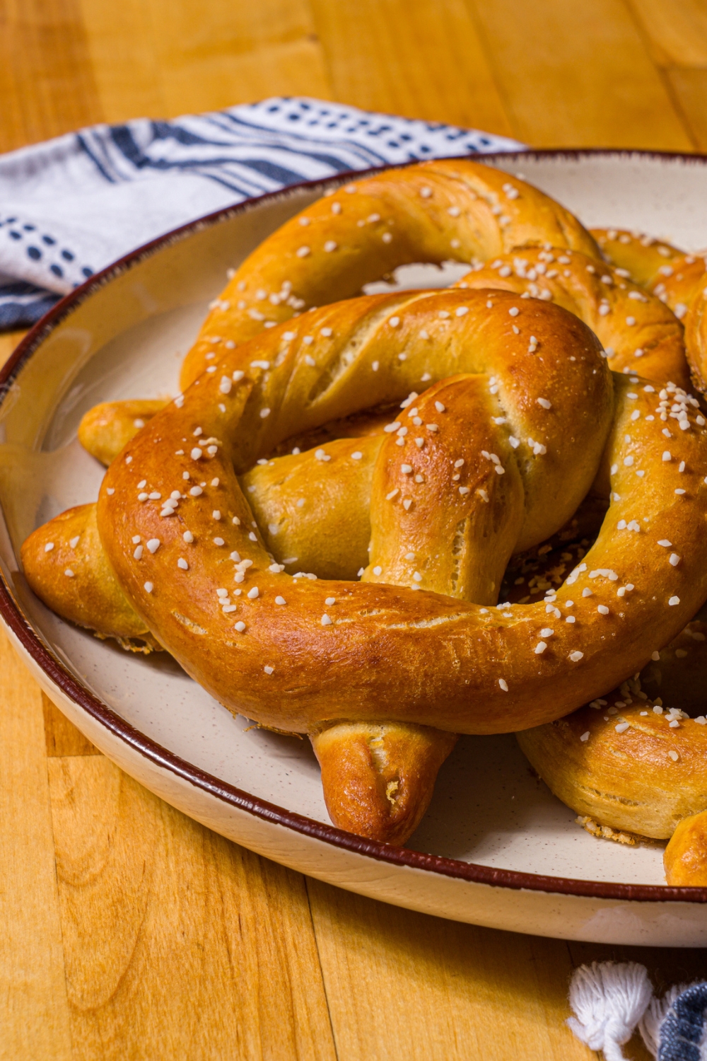 A white plate with copycat Auntie Anne's pretzels on a blue striped napkin on a wood counter.