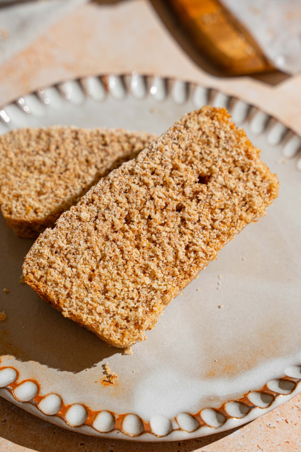 A white plate with two slices of Ezekiel bread. The plate is on a tan counter.