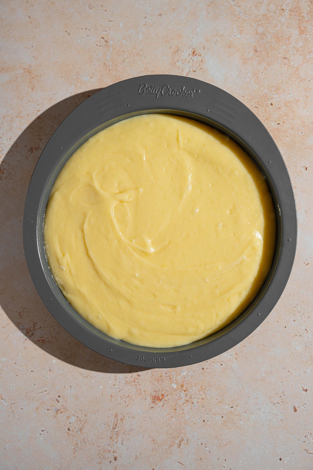 A cake pan with French butter cake batter. The pan is on a tan counter.