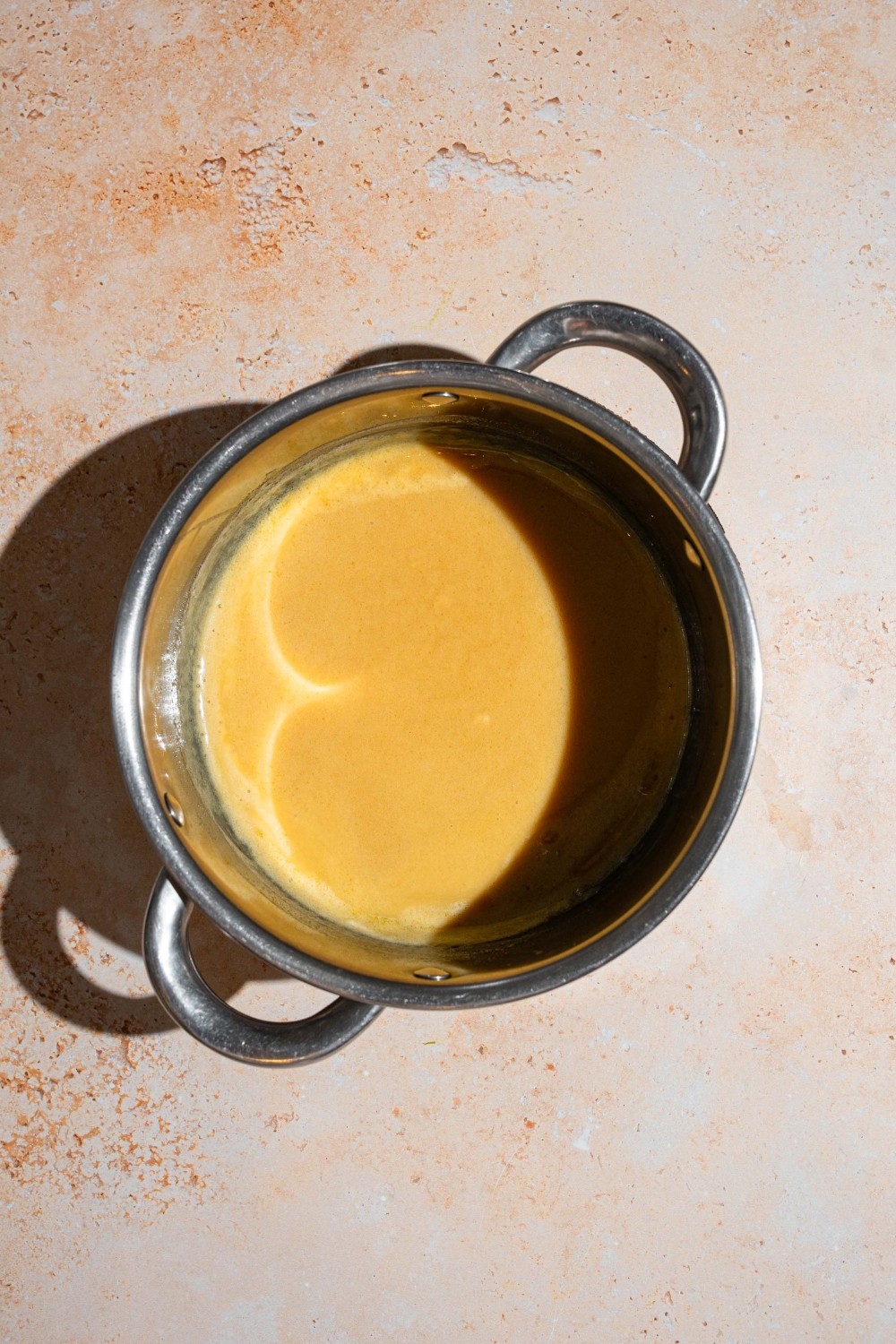 A pot with cooked rum sauce. The pot is on a tan counter.