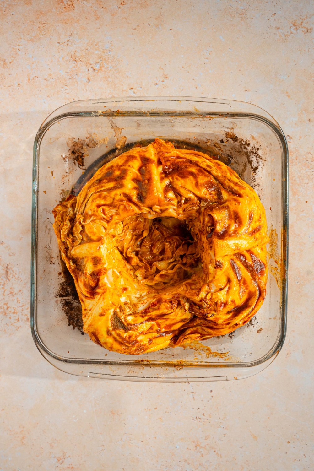 A baking dish with baked cabbage with cajun seasoned butter. The dish is on a tan counter.