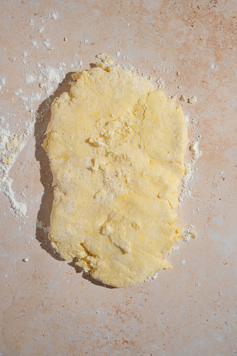 Shortcake dough rolled out over flour on a tan counter.