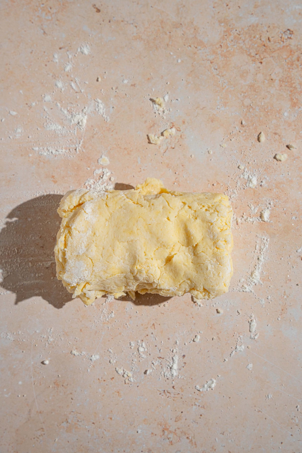 Folded shortcake dough on a tan counter with flour.