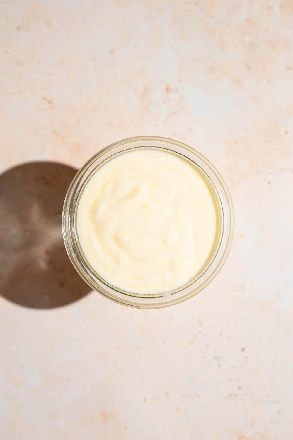 A jar of sour cream sauce. The jar is on a tan counter.