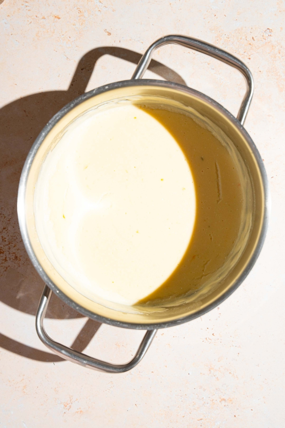 A stock pot with cooked sour cream sauce. The pot is on a tan counter.