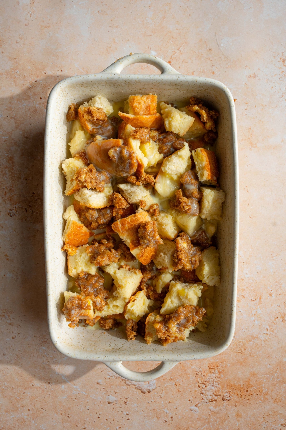 A ceramic baking dish with unbaked sourdough french toast casserole soaking in a custard mixture. The dish is on a tan counter.