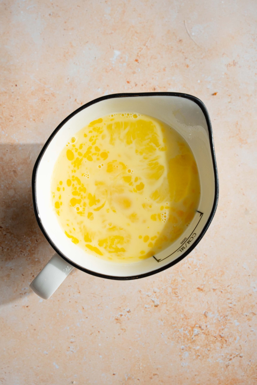 A large white bowl with an egg custard mixture. The bowl is on a tan counter.