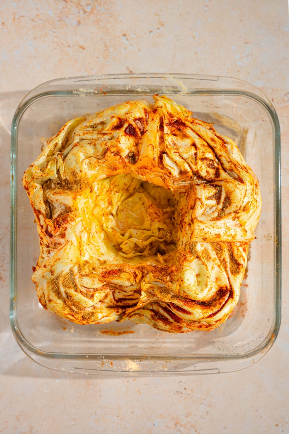 A glass baking dish with a prepared cabbage boil seasoned with cajun spices. The dish is on a tan counter.