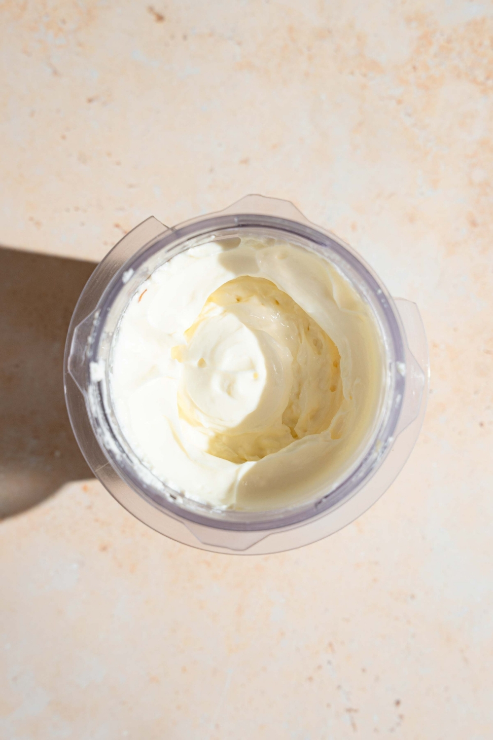 A blender with a whipped ricotta mixture. The blender is on a white counter.