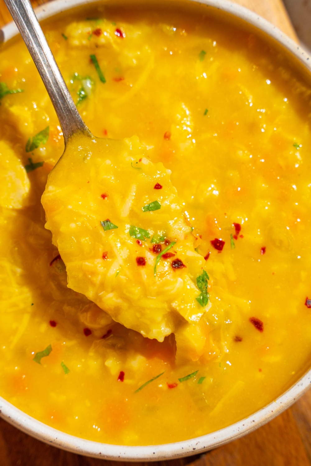 A white bowl of Italian penicillin soup garnished with fresh parsley and crushed red pepper. There is a spoon in the bowl.