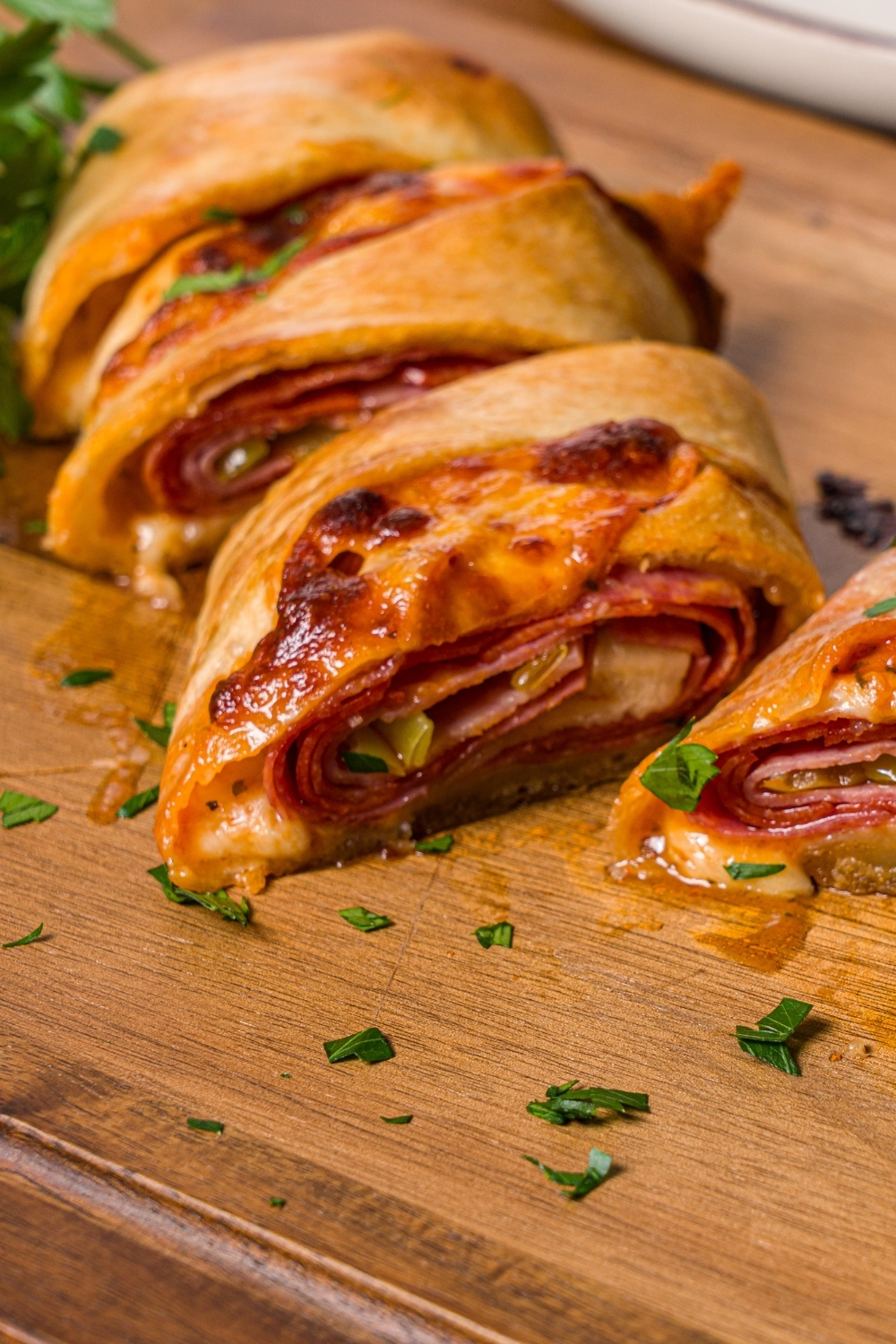 A wooden cutting board with sliced stromboli garnished with fresh parsley.