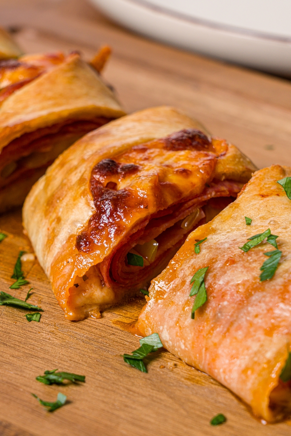A wooden cutting board with sliced stromboli garnished with fresh parsley.
