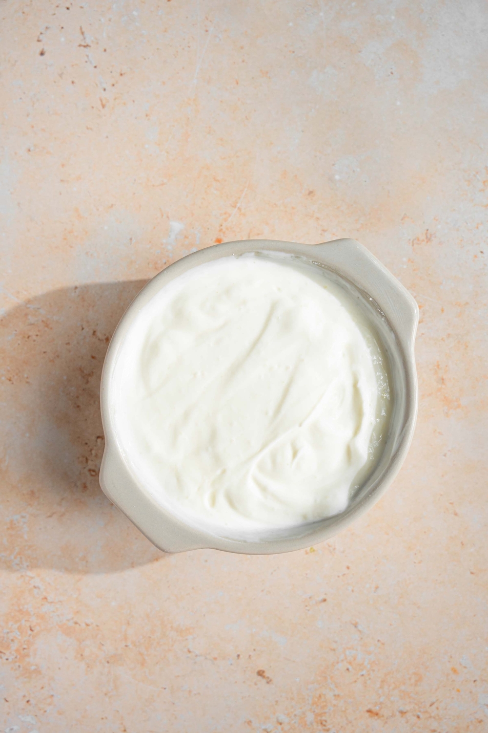 Yogurt in a white bowl on a white counter.