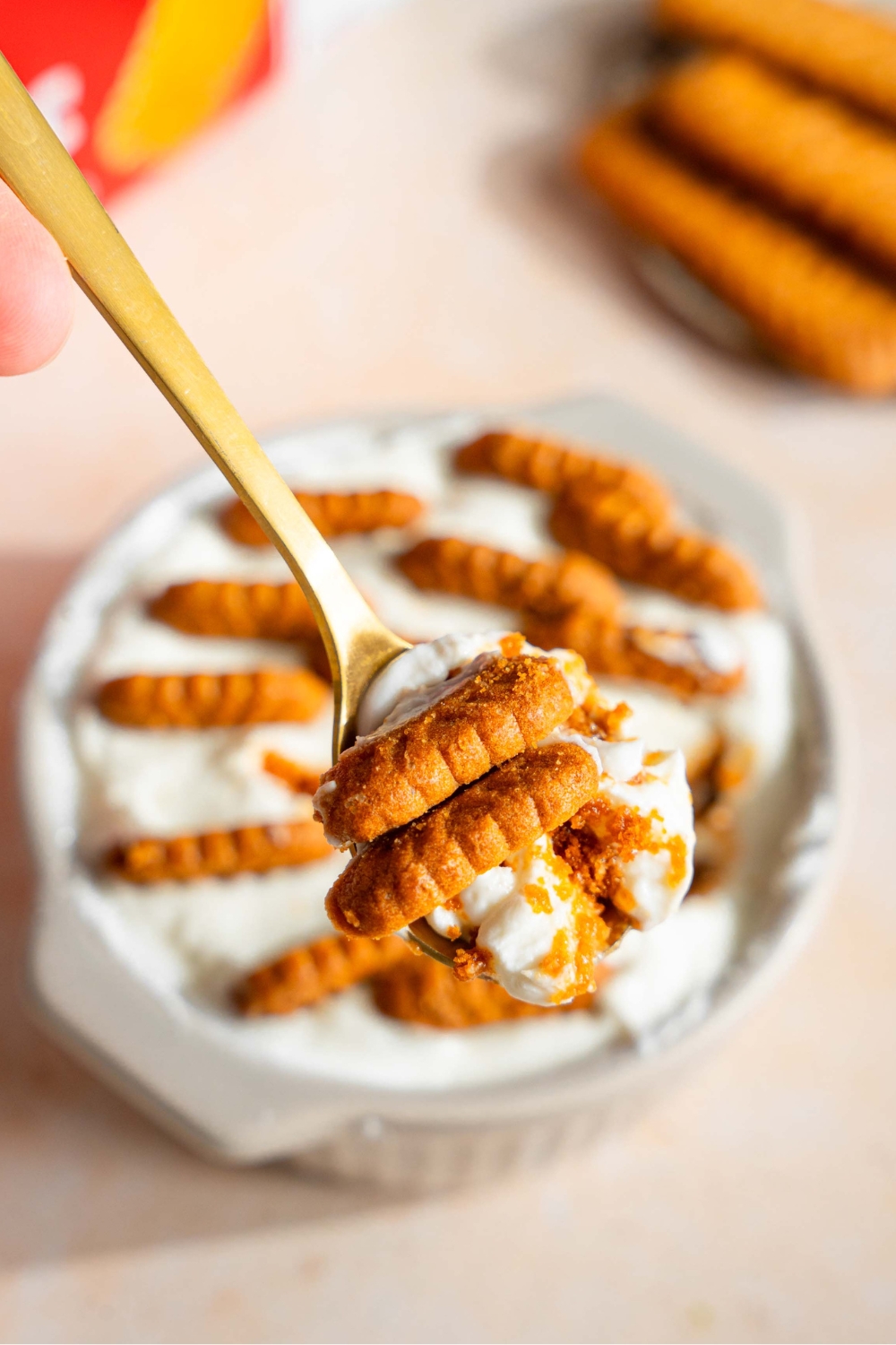 A spoon with Biscoff cookies and yogurt on it.