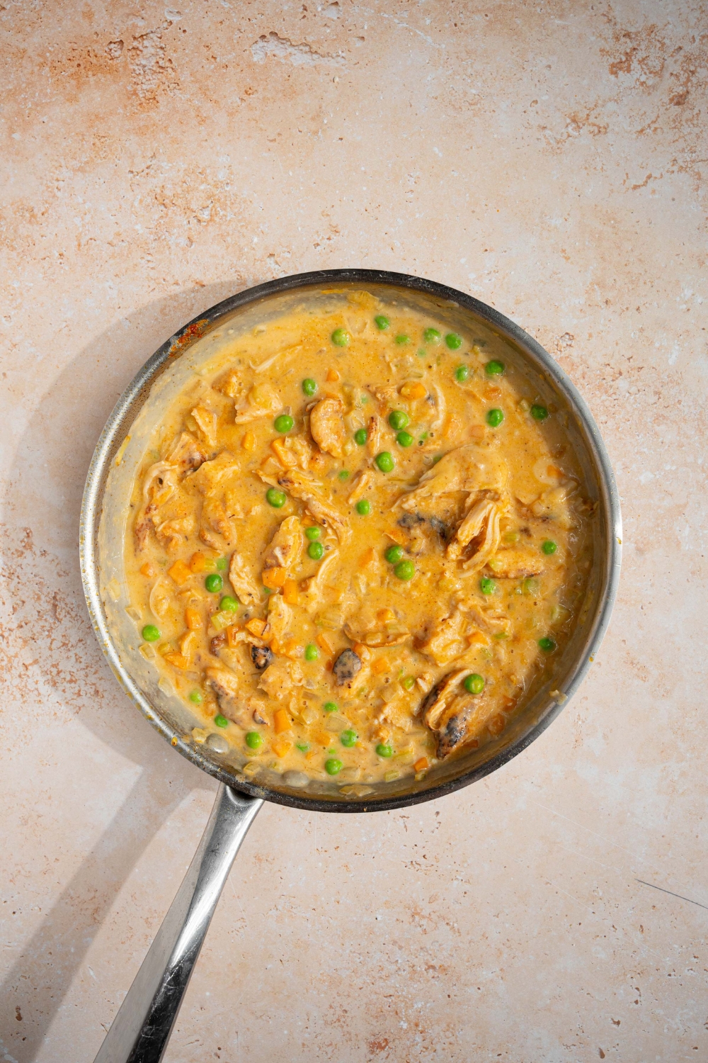 A skillet with cooked chicken pot pie filling. The skillet is on a tan counter.