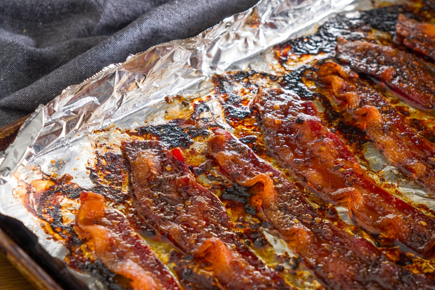 A baking sheet lined with foil with baked brown sugar bacon.