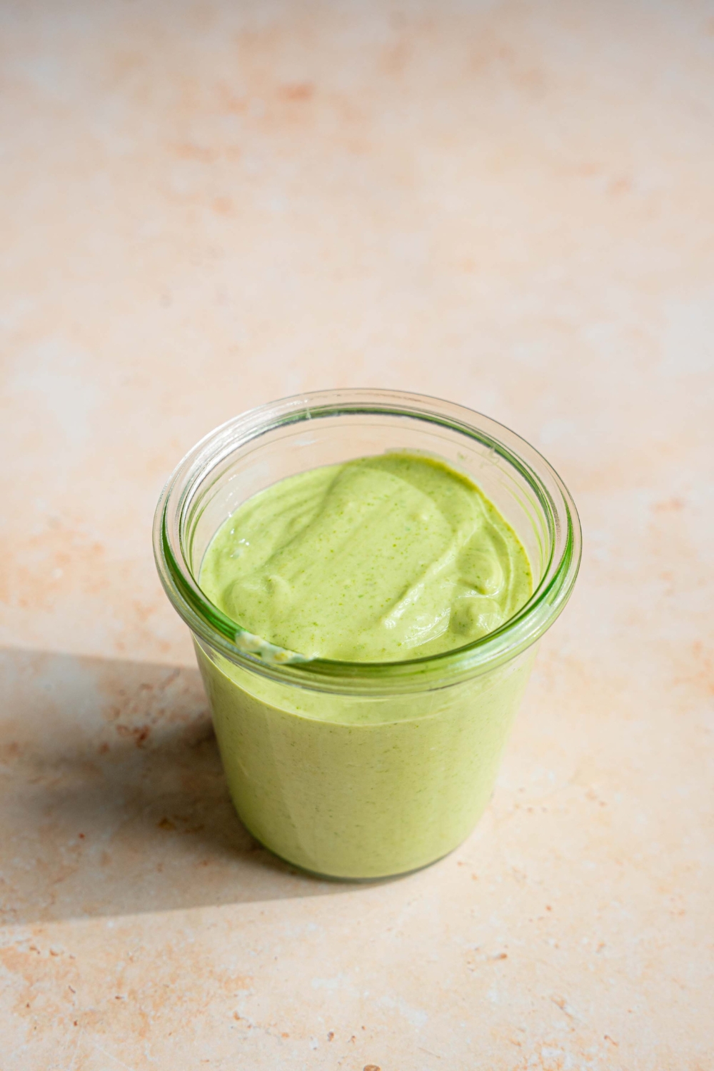 A jar of cilantro lime crema on a tan counter.