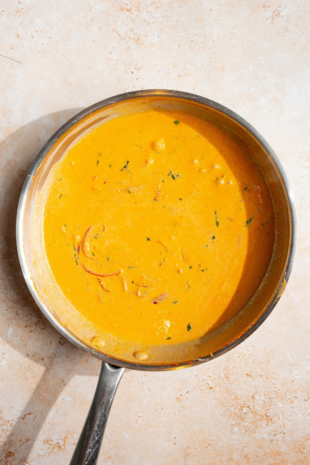 A skillet with thickened blush sauce. The skillet is on a tan counter.