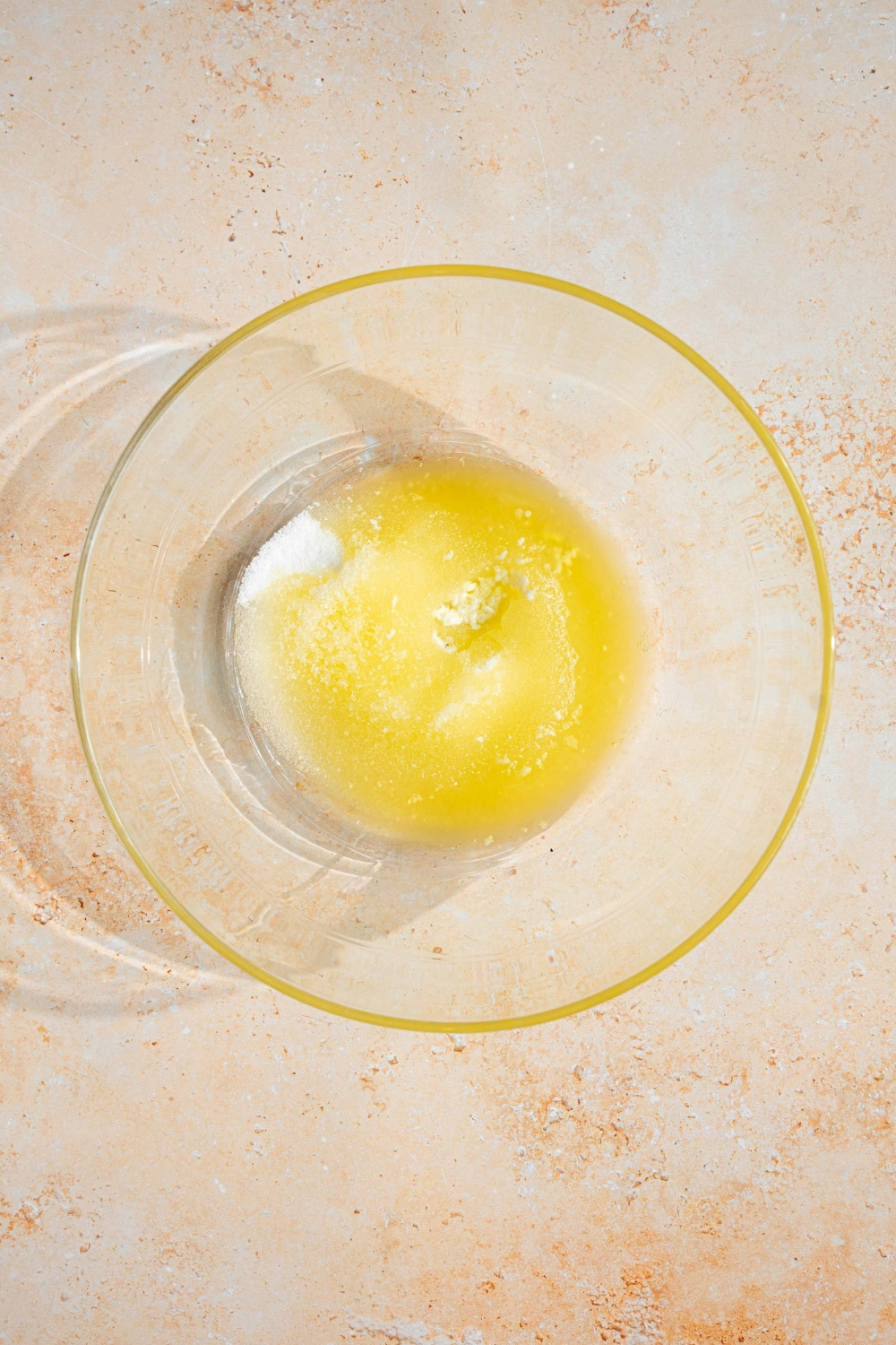 A glass bowl with a butter and sugar mixture. The bowl is on a tan counter.