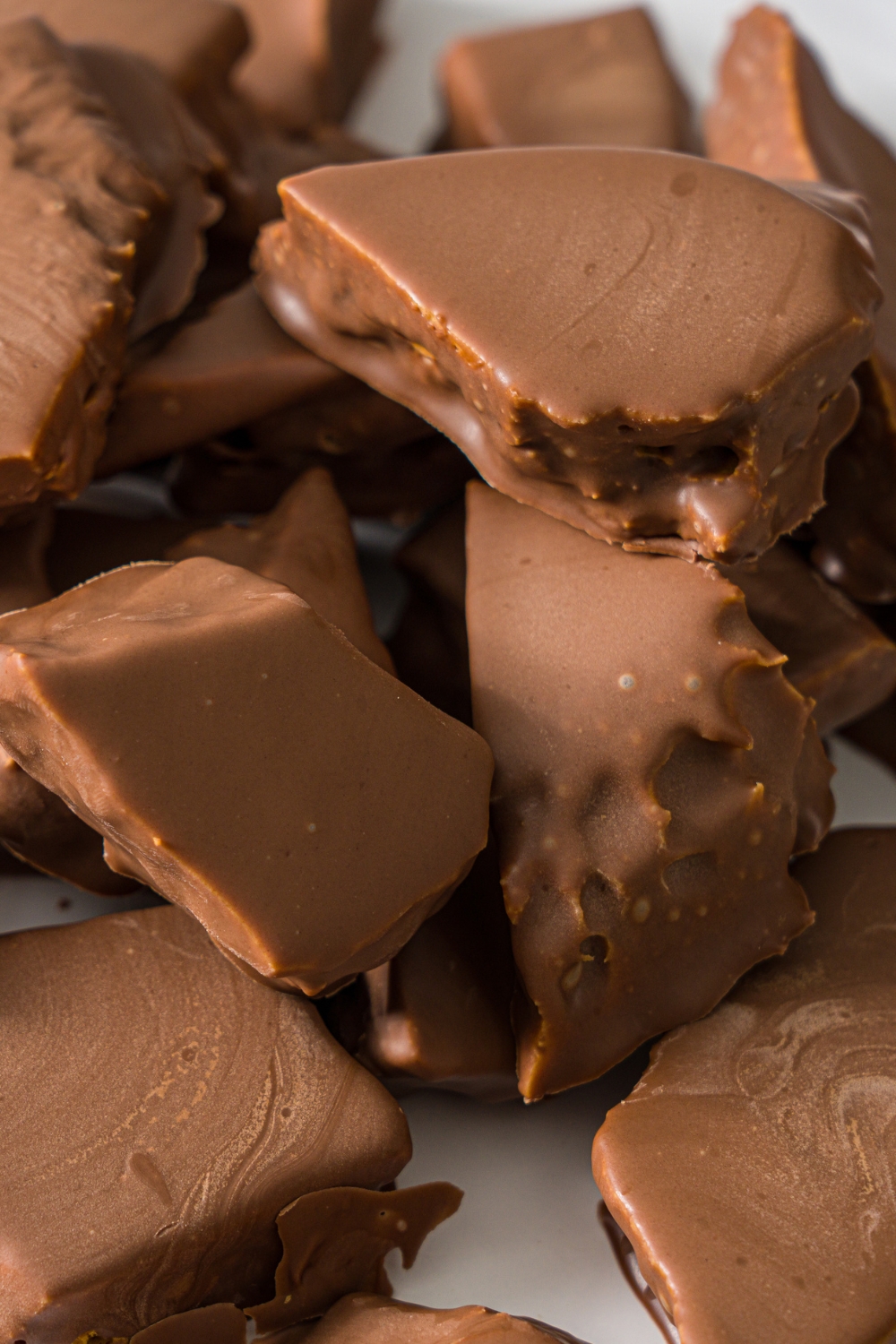 A white plate with sponge candy covered in milk chocolate.