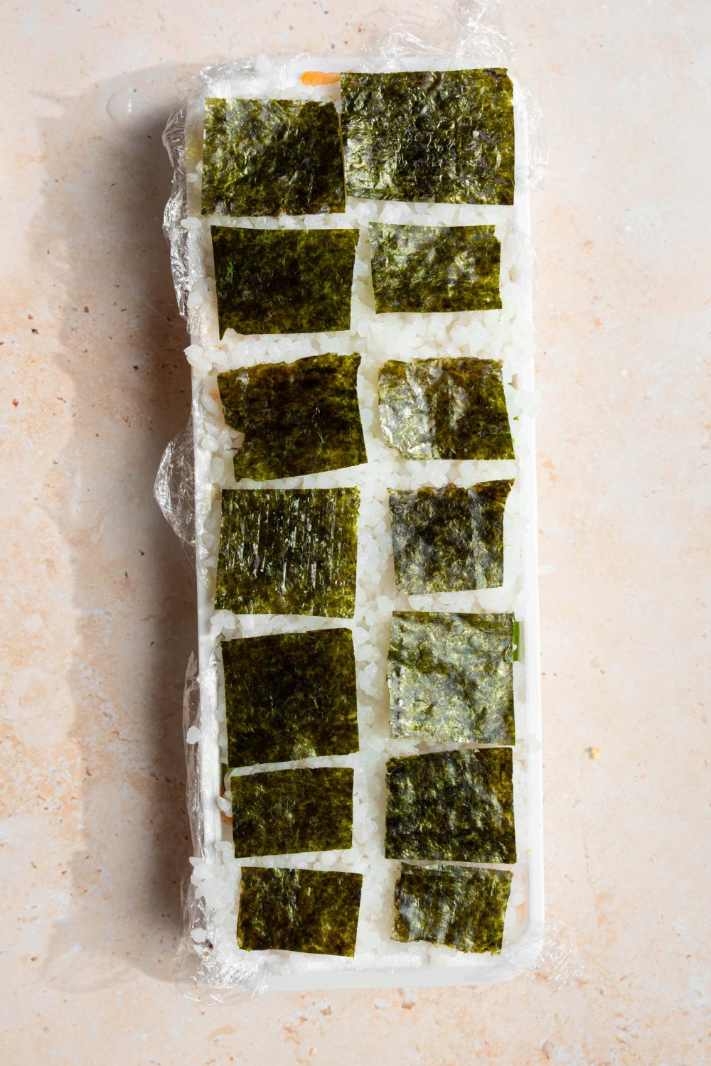An ice cube tray with sheets of nori in each slot.