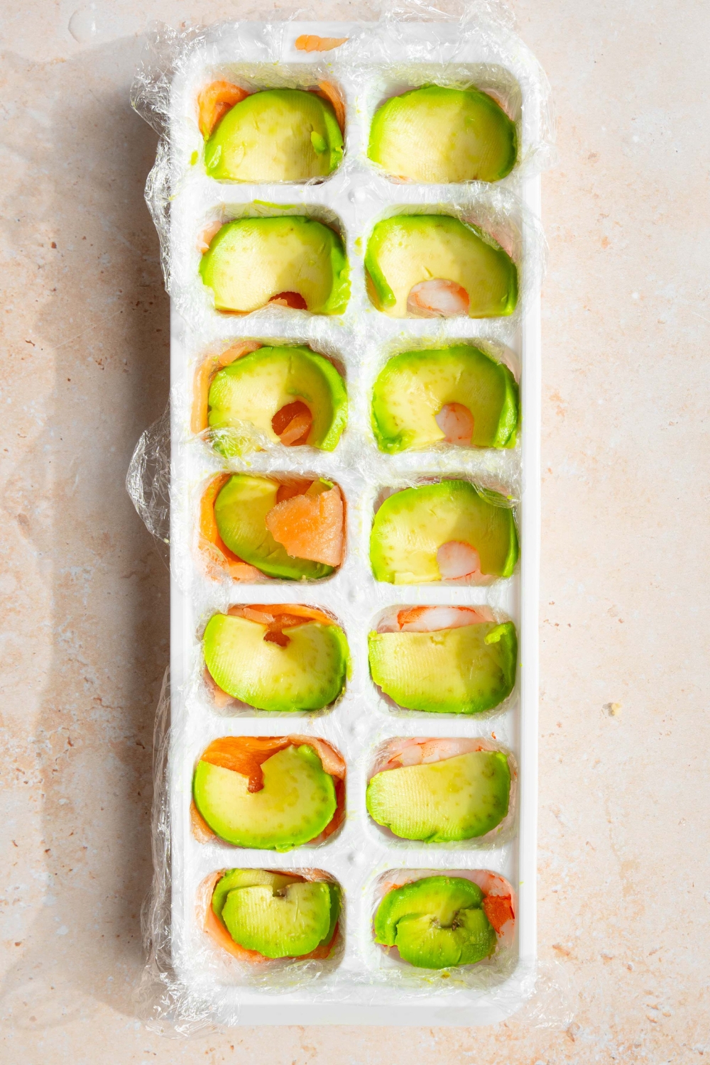 Avocado slices in the slots of an ice cube tray.