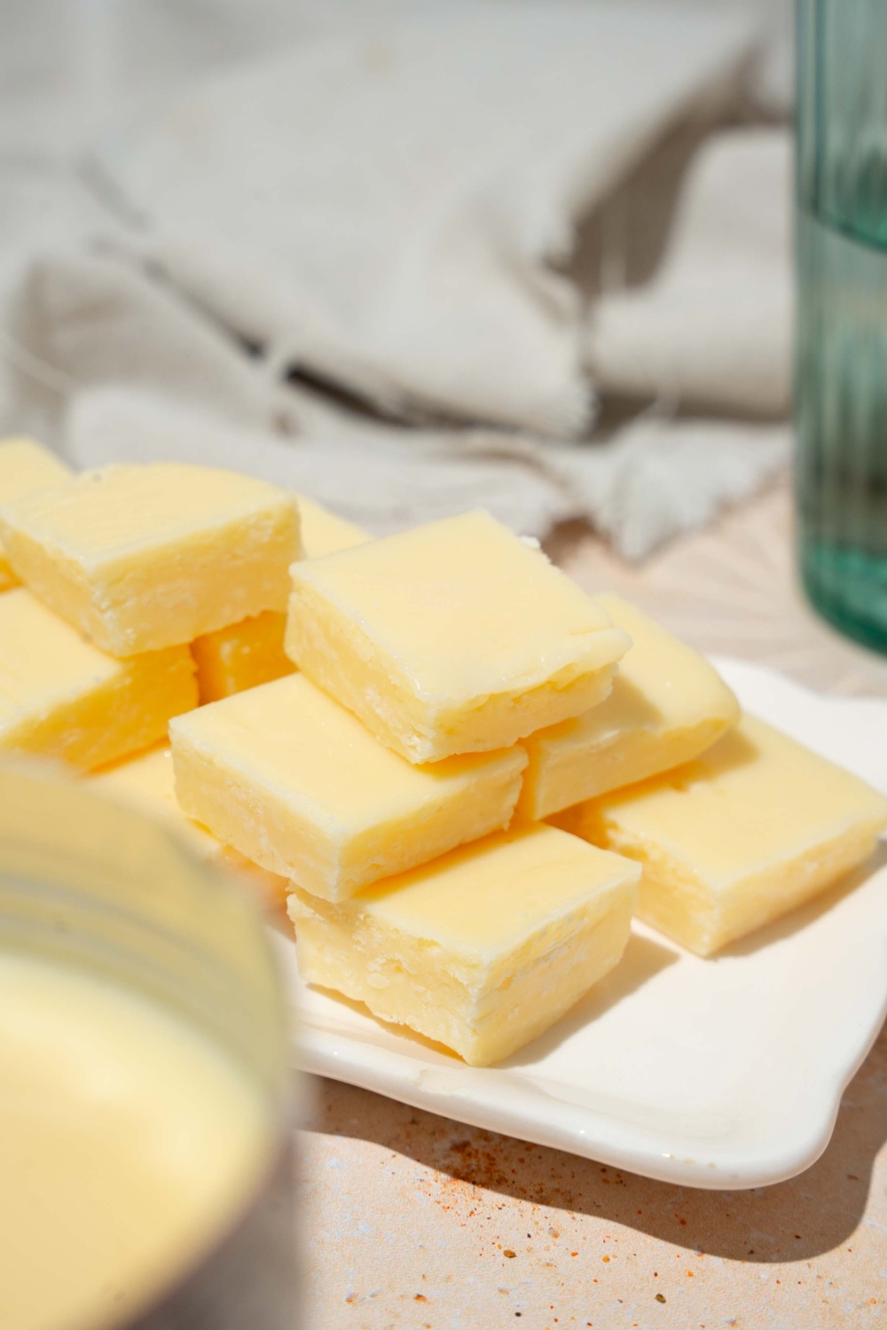 A white tray with pieces of vanilla fudge. The tray is on a tan counter with a white cloth napkin.