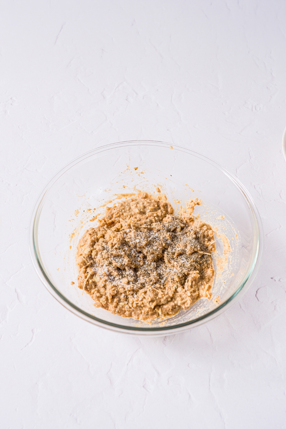 A glass bowl with a breadcrumb mixture for meatloaf. The bowl is on a marble counter.
