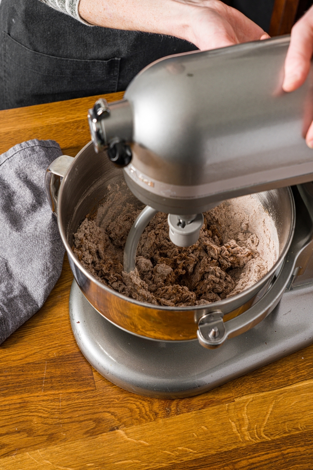 A mixer kneading Outback sweet molasses brown bread dough ingredients. The mixer is on a wooden board.