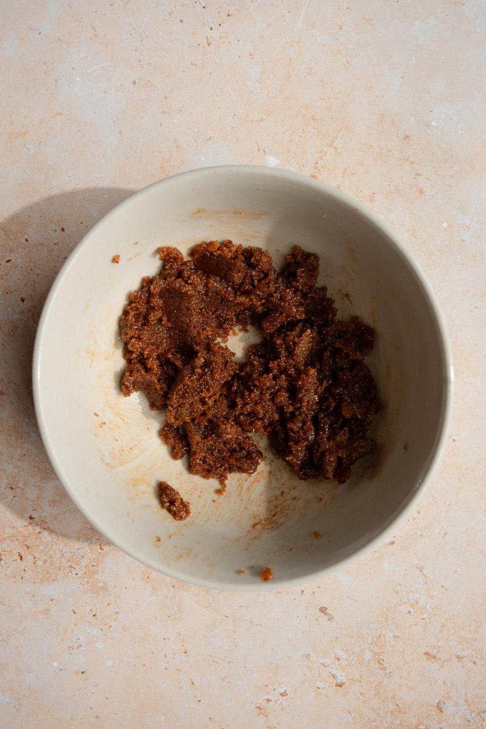 A bowl with a cinnamon and brown sugar mixture. The bowl is on a tan counter.