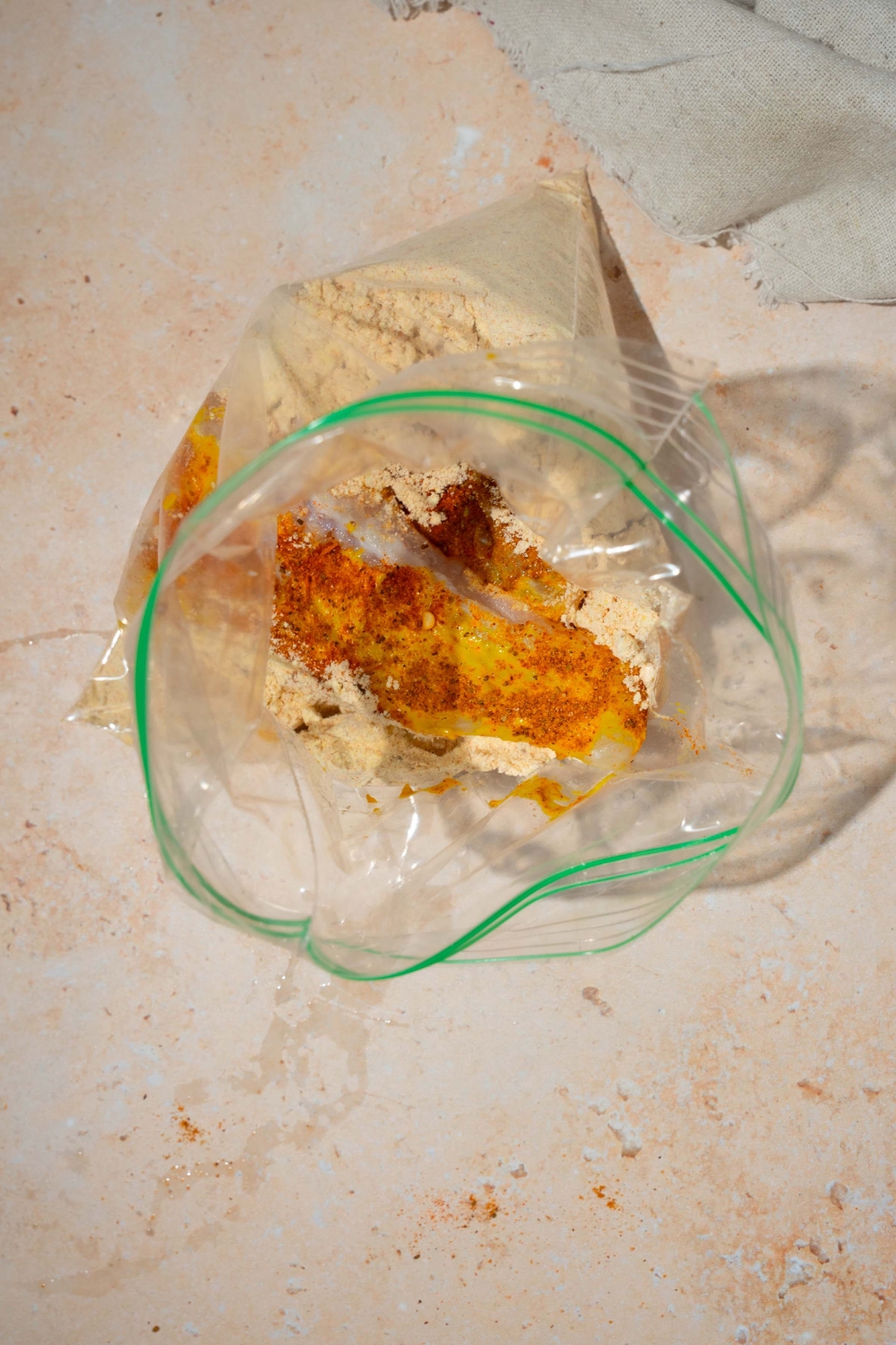 A plastic bag with ingredients for fish fry mix. The bag is on a tan counter.