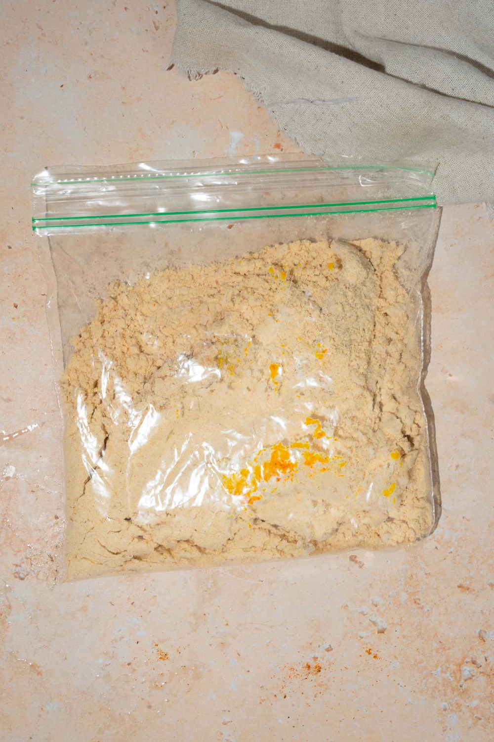 A plastic bag with fish fry seasoning. The bag is on a tan counter.