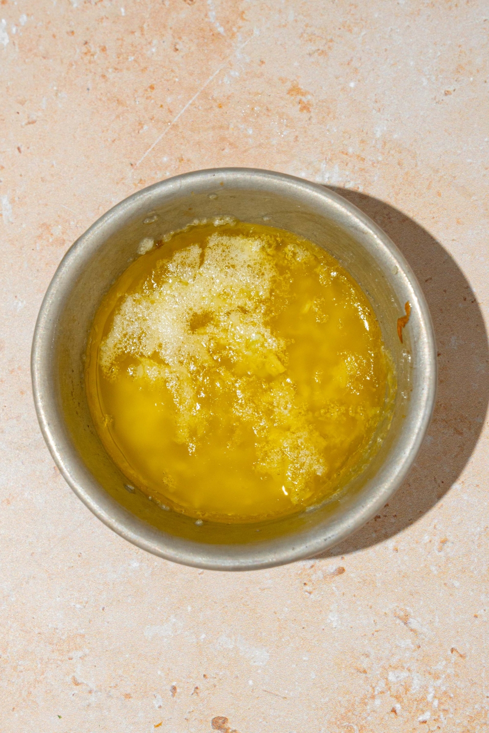 A small white bowl with garlic parmesan butter. The bowl is on a tan counter.
