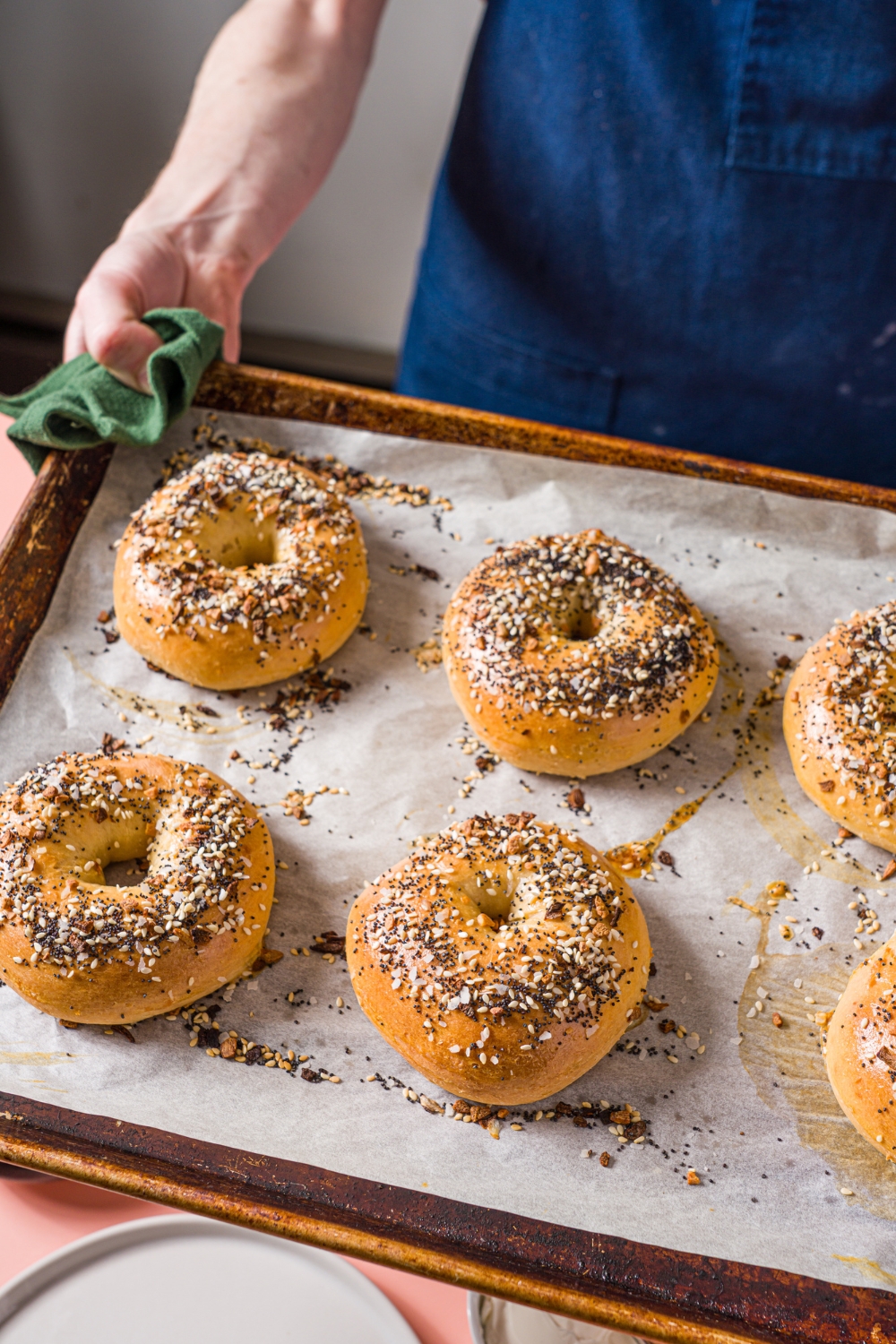 A baking sheet lined with parchment paper with several baked greek yogurt everything bagels.