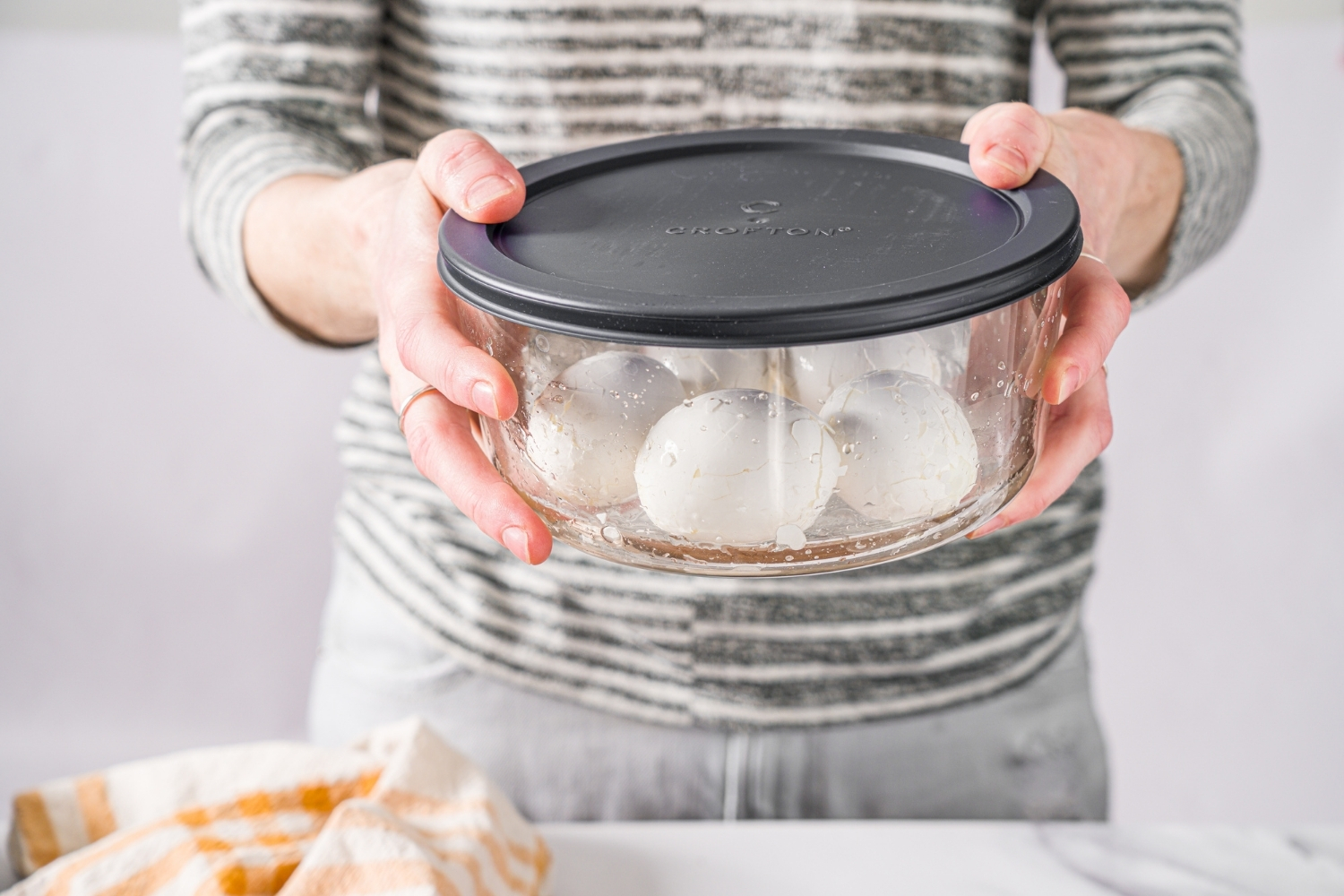 A large sealed pyrex bowl with several hard boiled eggs being shaken in the bowl.