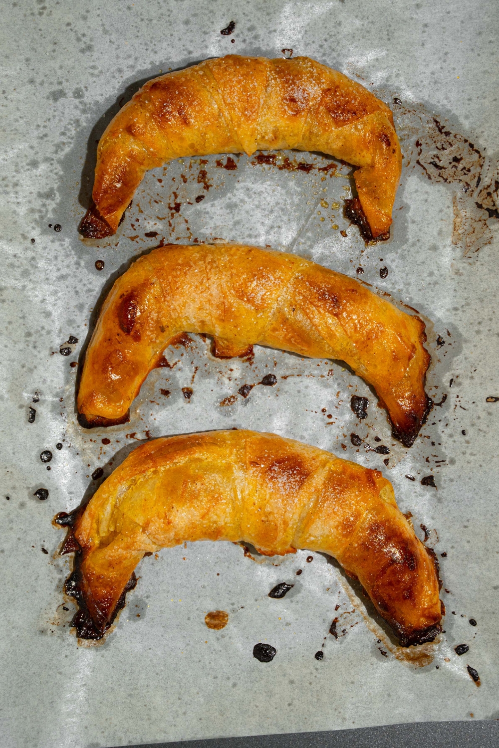 A baking sheet with parchment paper with three baked rice paper croissants.