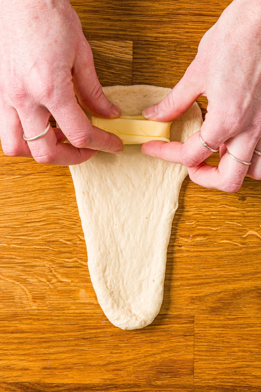 A piece of butter on a rolled out piece of salt dough. The dough is on a wooden counter.